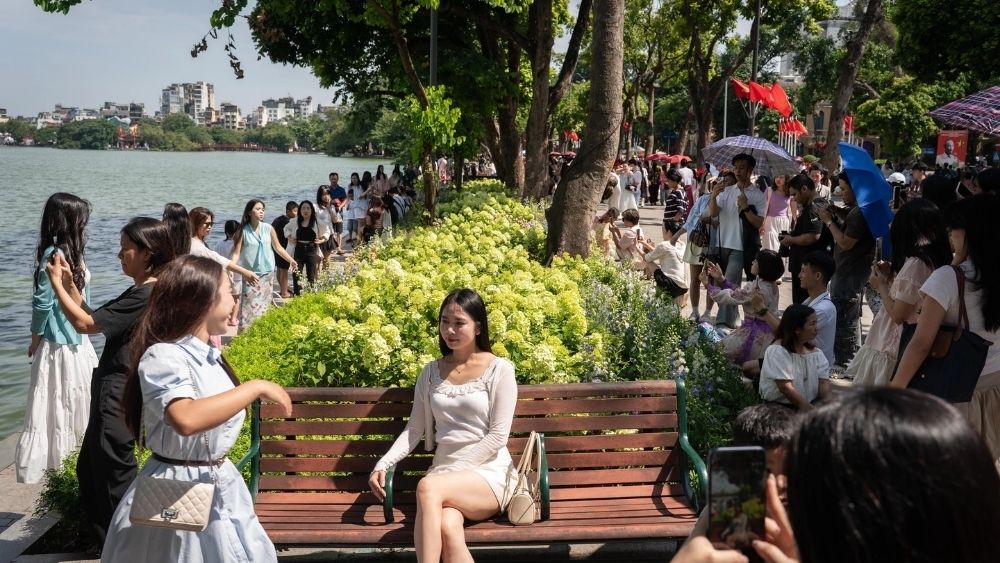 Du khách xếp hàng chờ chụp ảnh cùng hoa cẩm tú cầu bên hồ Gươm, bất chấp nắng nóng và thời gian chờ đợi.